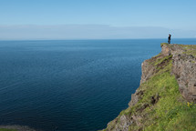 woman standing at the edge of a cliff overlooking the ocean 