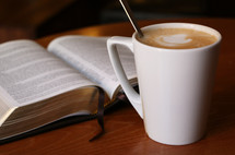 open Bible and cappuccino on a table 