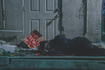 homeless man sleeping on a sidewalk