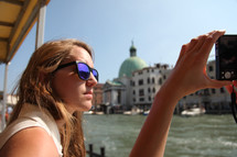 woman taking a picture with a camera from a boat in Venice 