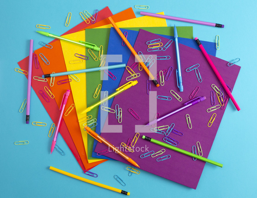 rainbow colored paperclips, pencils, and paper 