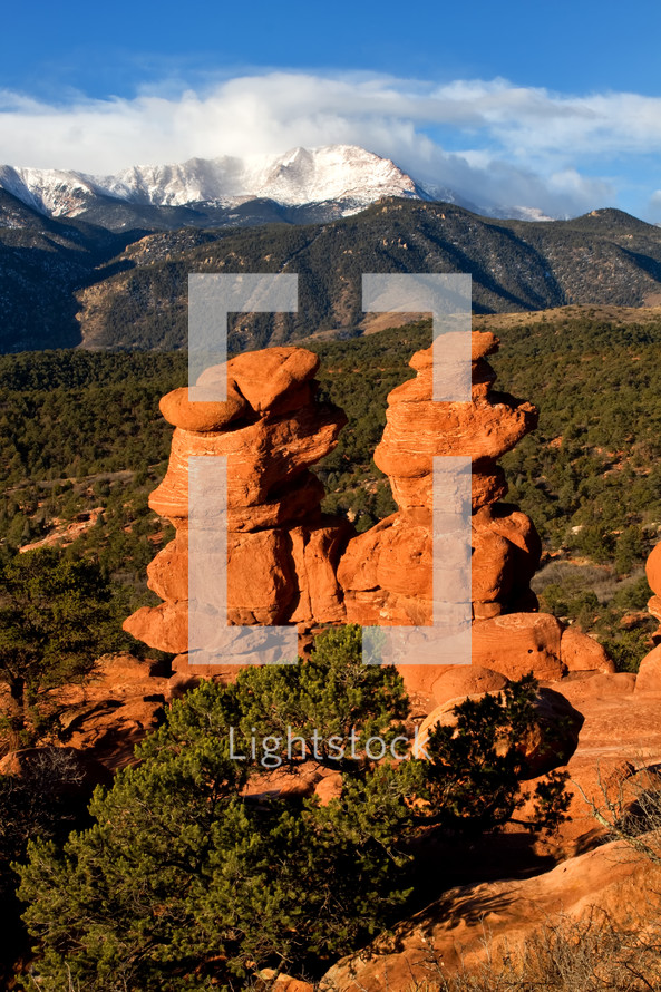 clouds over snow capped mountain peaks and red rock formations 