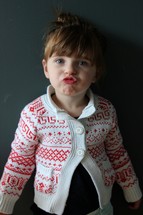 toddler girl standing in front of a chalkboard making a silly face 