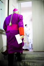 Priest walking up steps.