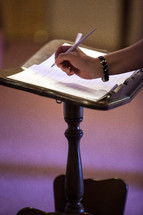 Woman signing a document on a podium