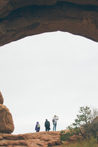 people standing under a nature stone arch 