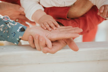 father and mother hold a baby's hand