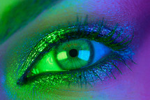 Extreme close up female eye iris under neon light. Woman with beautiful makeup
