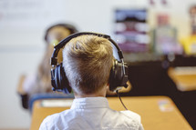 students sitting in a classroom wearing headphones 