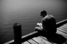 A young man studies the Word on a dock by the still water