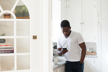 African American man texting on his cellphone in a kitchen 
