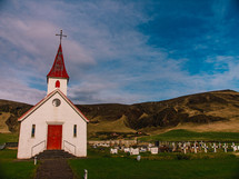 white church with a red steeple and cemetery 