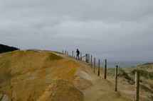 A person walking along the top of a sand dune.