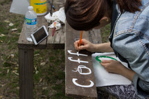a teen girl painting a sign 