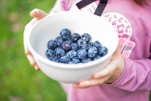 a girl holding a bowl of blueberries 