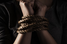 Wrists bound by rope.