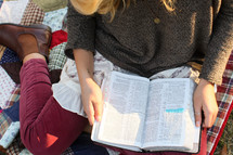 woman sitting on a blanket reading a Bible 
