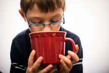 a boy sipping from a mug 