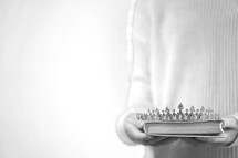 a woman holding a tiara and Bible 