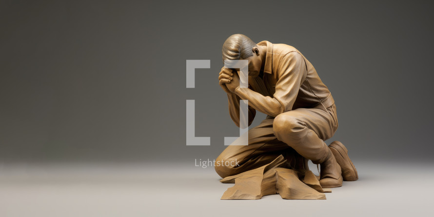 Man praying on the floor in front of a grey background