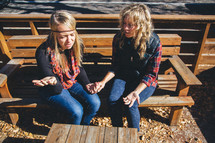 friends sitting on a bench holding hands in prayer 