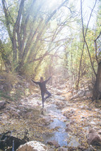 a woman balancing on stones in a creek 