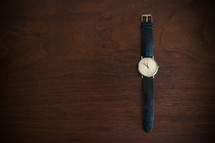 Wristwatch on a wooden table.