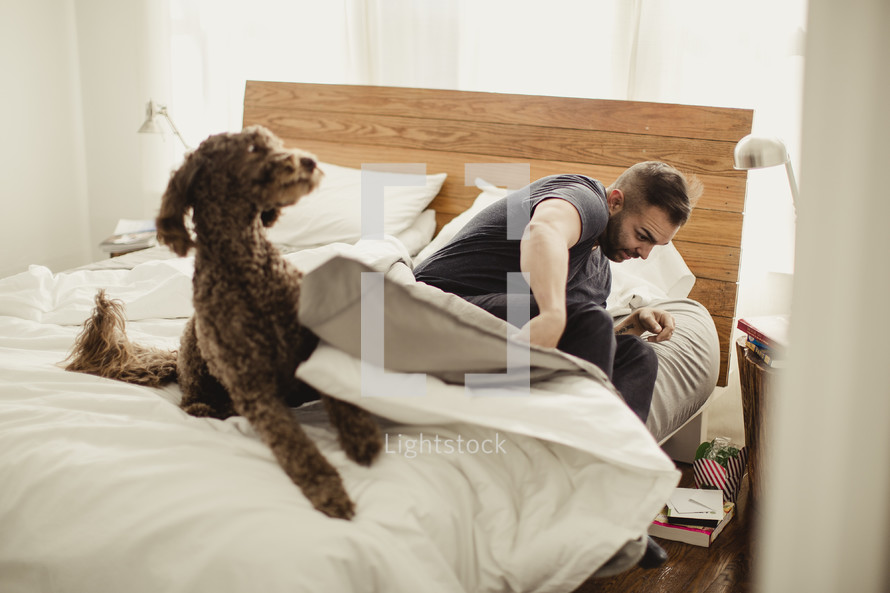 Man rising out of bed with dog.