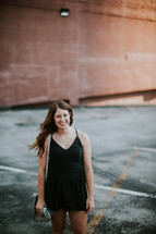 a young woman in a romper standing in a parking lot 