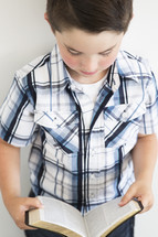 a boy child reading a Bible 