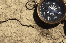 A  compass on a cracked, bare ground.