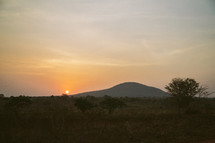 a sun setting behind a hill in Africa 