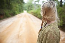 Woman looking at open dirt road 
