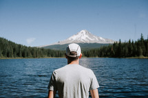 man standing in front of a mountain lake 