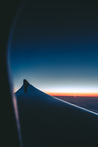 wing of a plane through a window at dawn