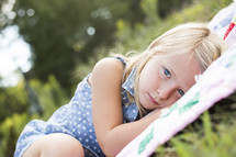 girl child lying on a blanket in the grass 