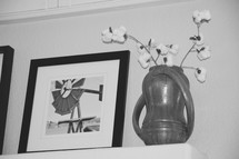 framed windmill photograph and cotton sprays in a pottery vase on a mantel 