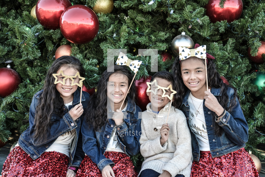 siblings posing in front of a Christmas tree 