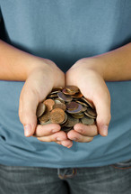 A young person holding out a hand full of coins