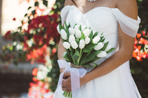 torso of a bride holding white tulips 
