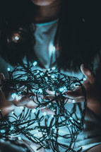 a girl holding a string of lights 