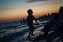 Kid playing on the beach at sunset
