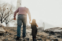 a grandfather walking holding hands with his granddaughter 