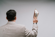 a pastor holding up a Bible preaching 