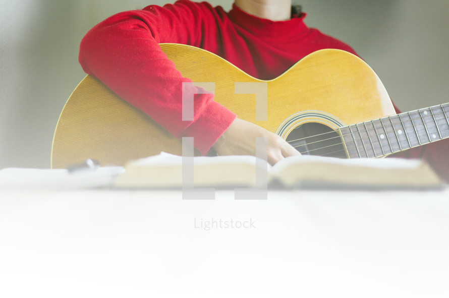 a person reading a Bible and playing a Guitar 