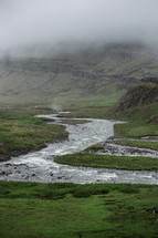 flowing stream in a foggy landscape 