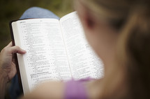 An over the shoulder view of a woman reading her Bible