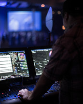 A sound technician in a sound booth during a church service.
