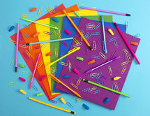 pencils, erasers, paperclips, and paper in rainbow colors 