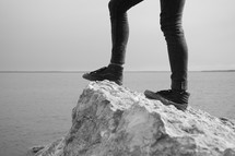 feet standing on a rock by water 